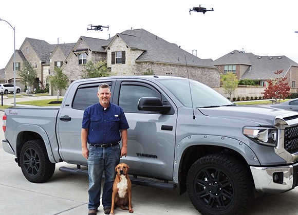 Scott Crowers, professional home inspector, with his dog Riley and two drones hovering in the air.